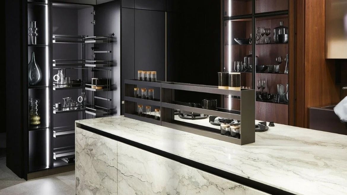 Modern kitchen with a marble island, dark cabinetry, and glass-front wine storage.