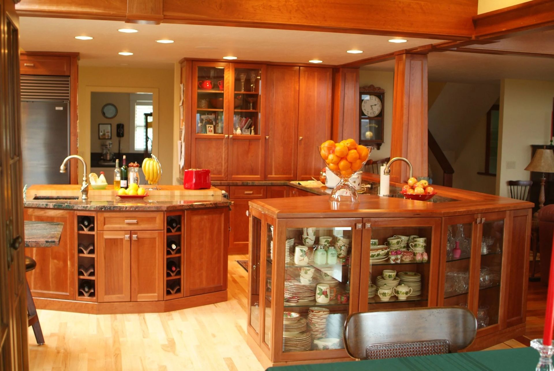 Warm wood kitchen with island, cabinets, sink, and fruit bowl under recessed lighting