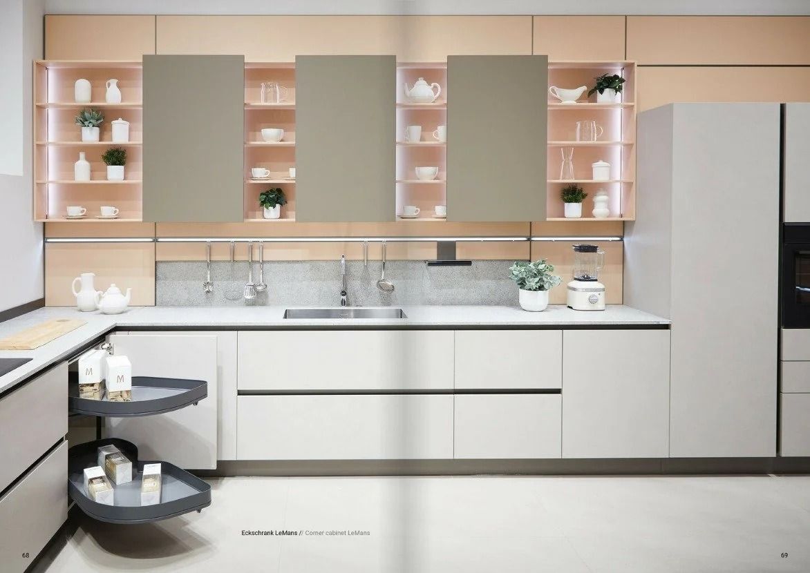Modern beige kitchen with pink shelving, white cabinetry, and a stainless steel refrigerator