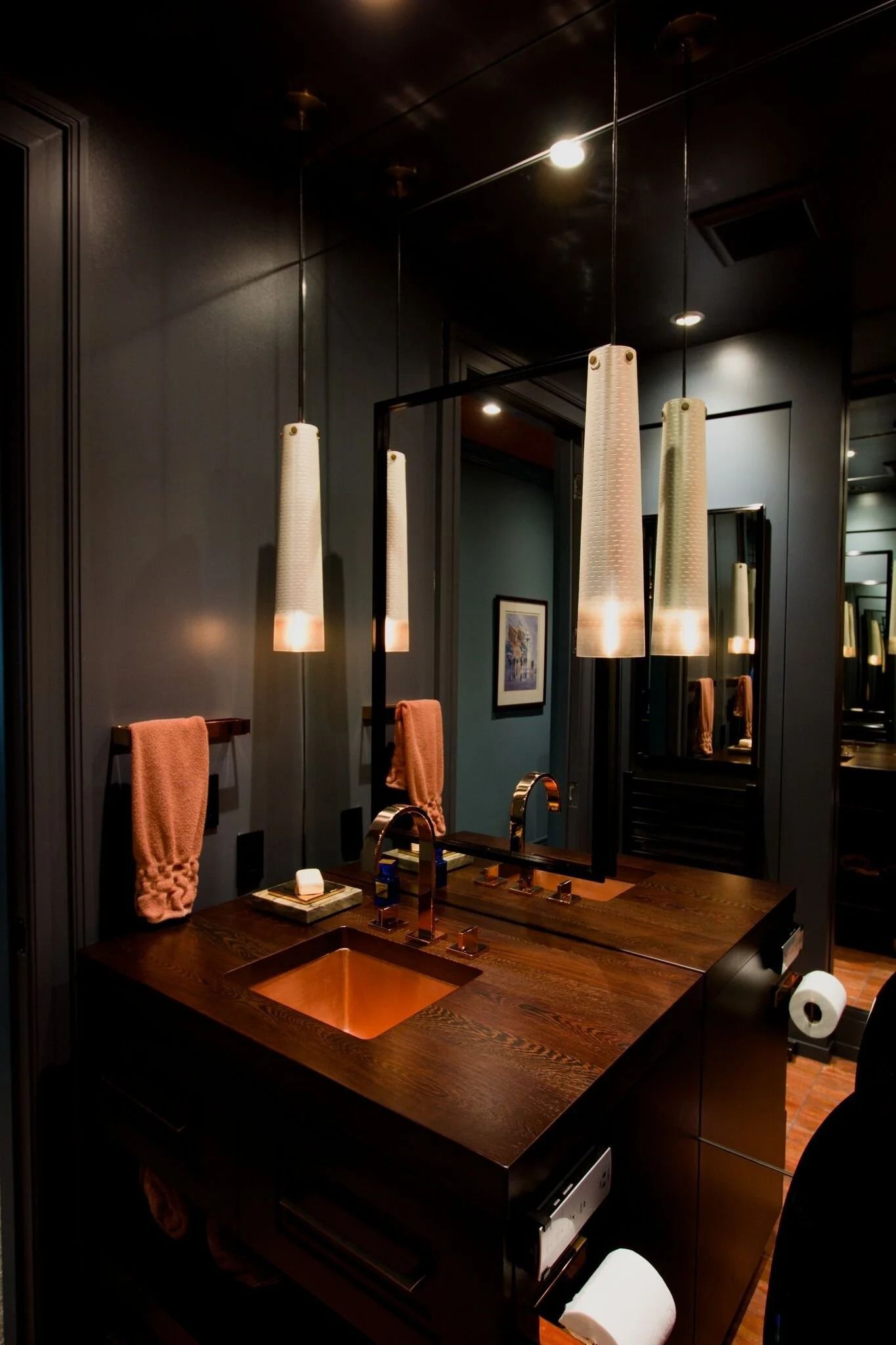 Modern black bathroom with dark wood vanity, mirror, and hanging pendant lights