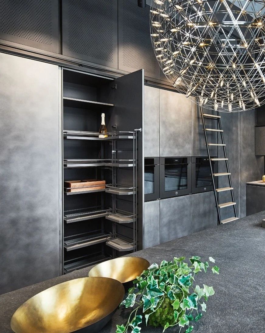 Modern gray kitchen with open shelving, ladder, brass bowls, and a large geometric pendant light