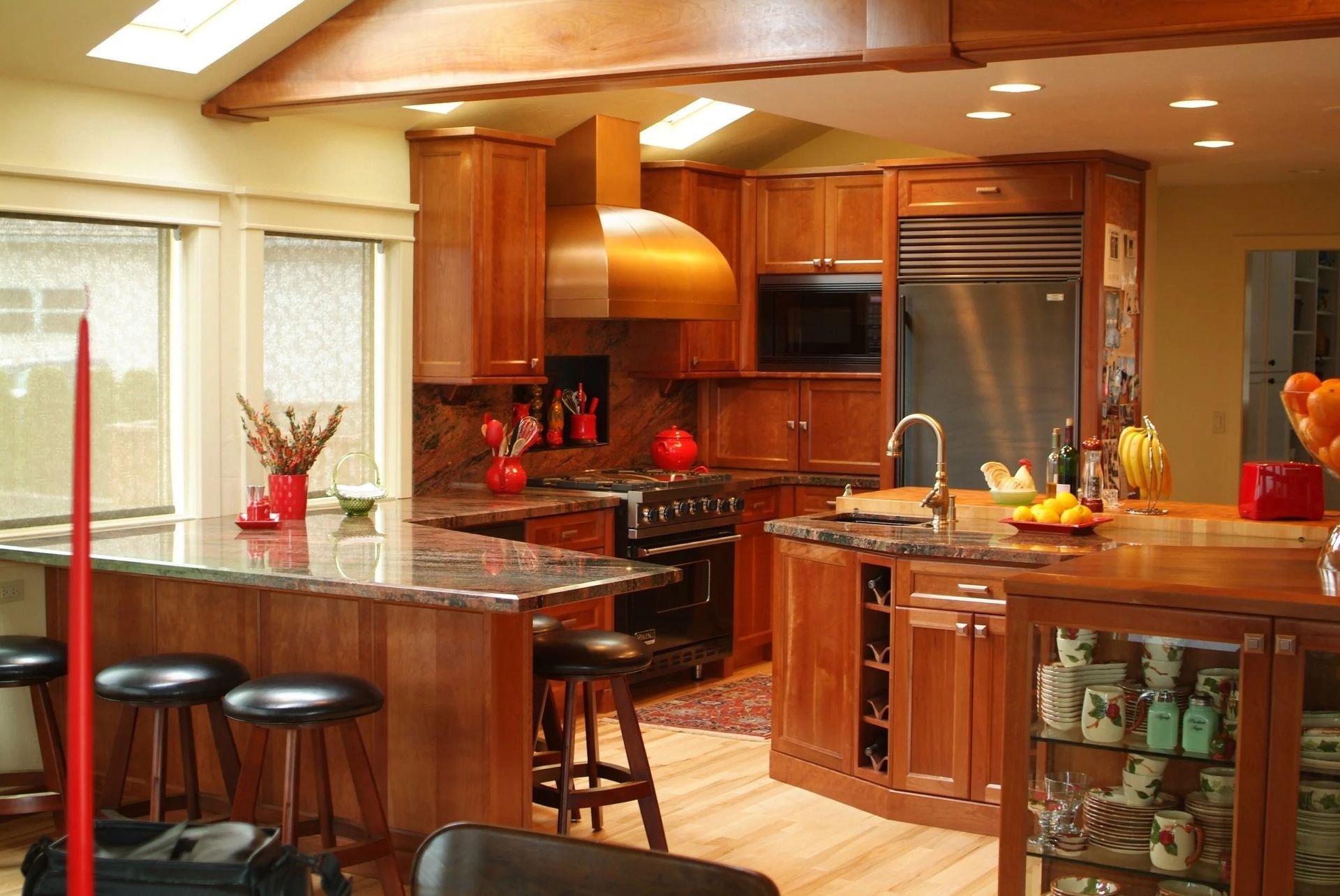 Warm kitchen with wood cabinets, granite island, bar stools, and stainless-steel appliances