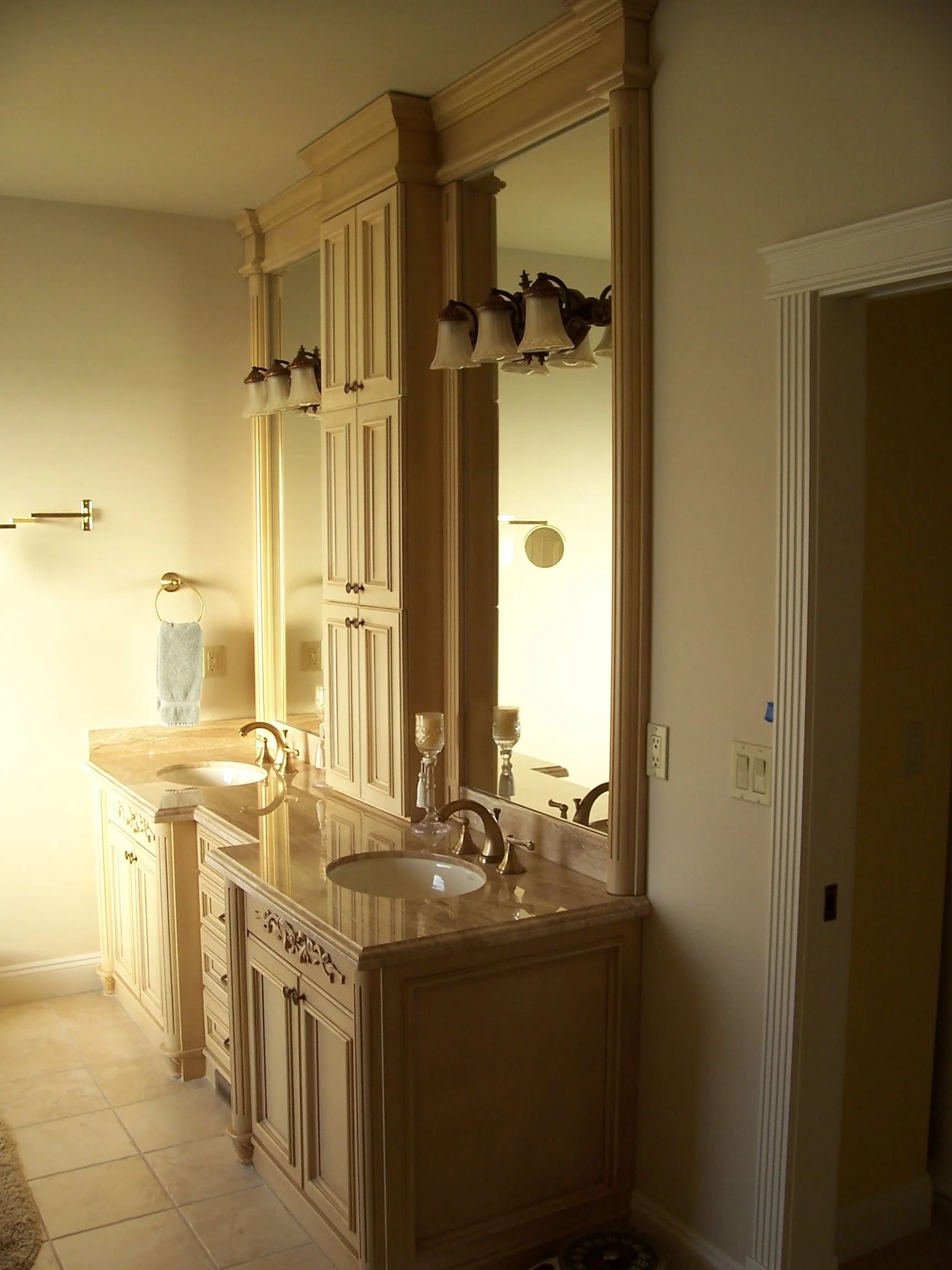 Bathroom with beige vanity, large mirror, sink, and tiled floor in warm light