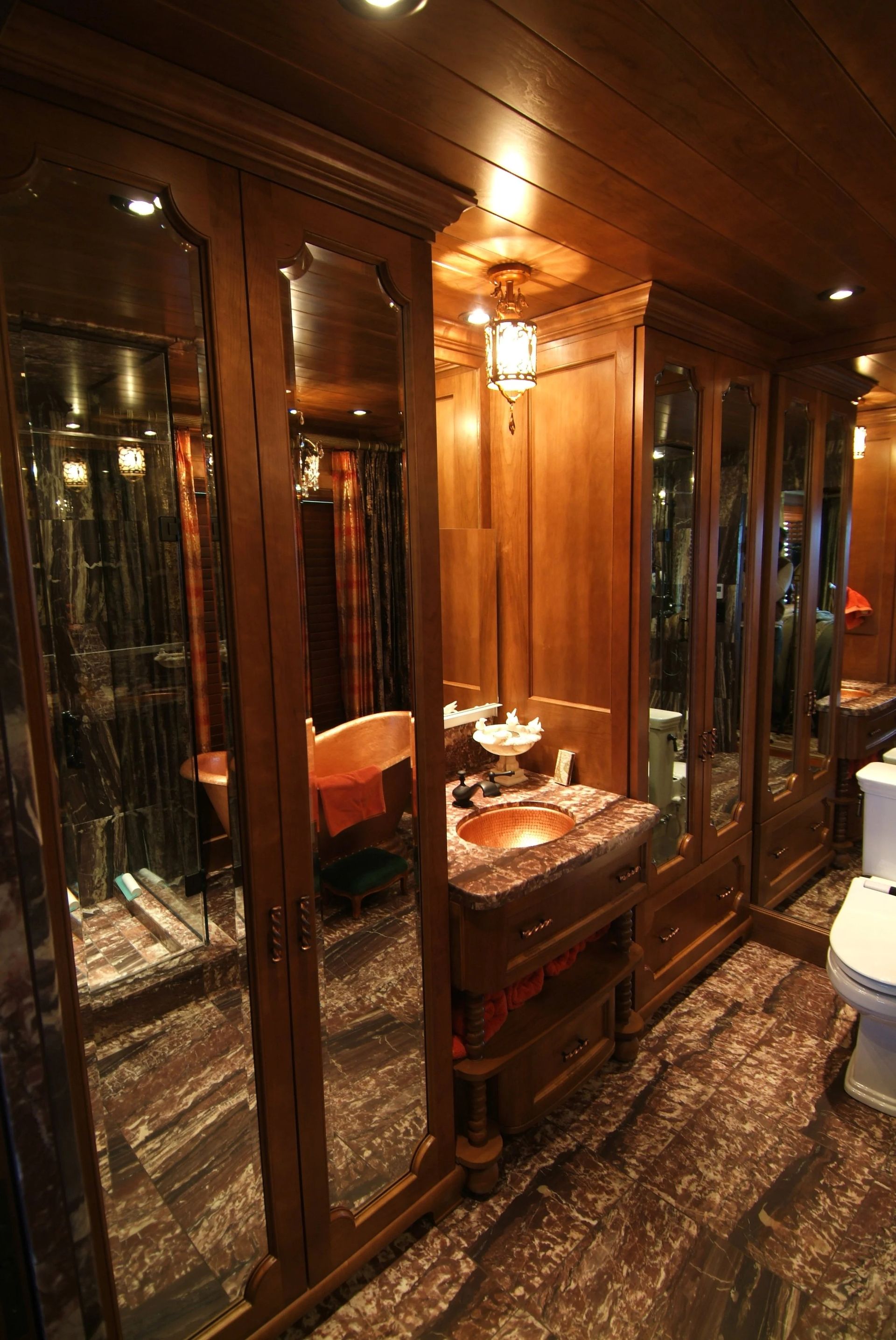 Wood-paneled interior with mirrored cabinets, a small table, and warm overhead lighting.