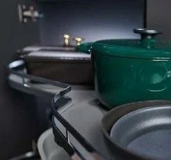 Kitchen cookware on a stove: a green pot, gray pan, and utensils on a counter