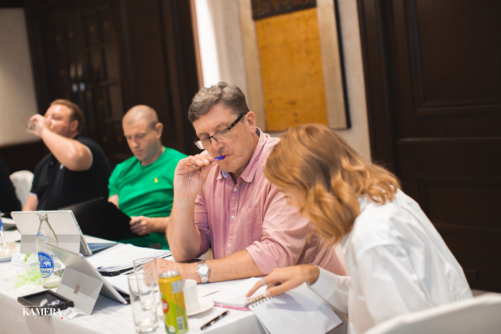 People collaborating at a table with laptops and papers in a meeting room