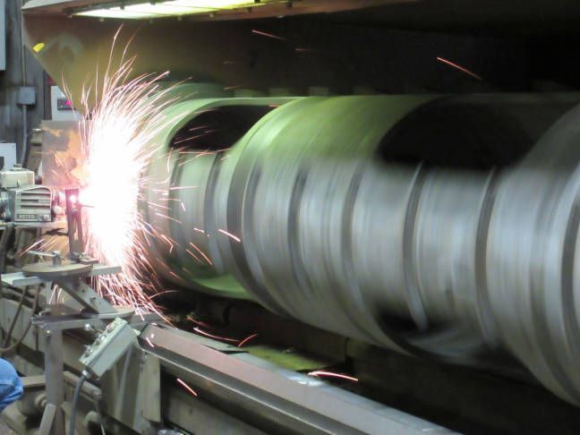 A metal part being coated using the Flame Spray process.
