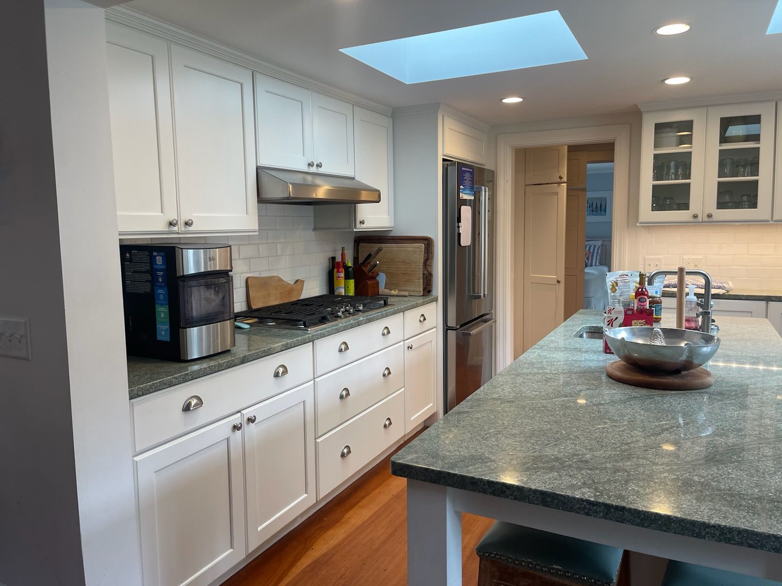 Bright modern kitchen with white cabinets, granite island, and a skylight above the counter.