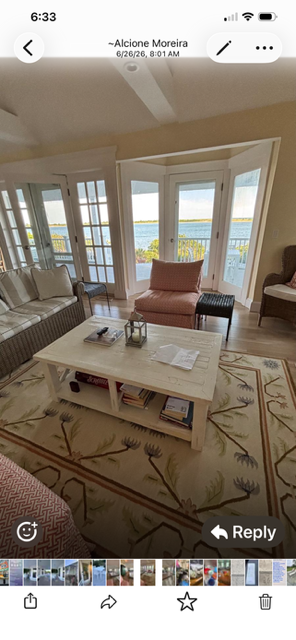 Bright living room with large windows, white sofa, pink chairs, and a coffee table on a patterned rug.