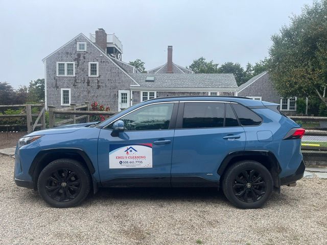 Blue SUV with company logo parked in front of a gray house on a gravel driveway