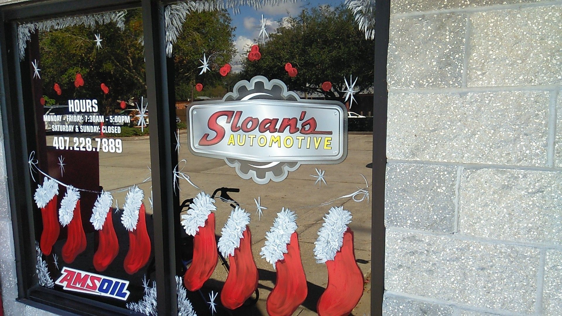 Sloan's Automotive store window with Christmas decorations: red stockings, snowflakes, and the business sign. | Sloan's Automotive