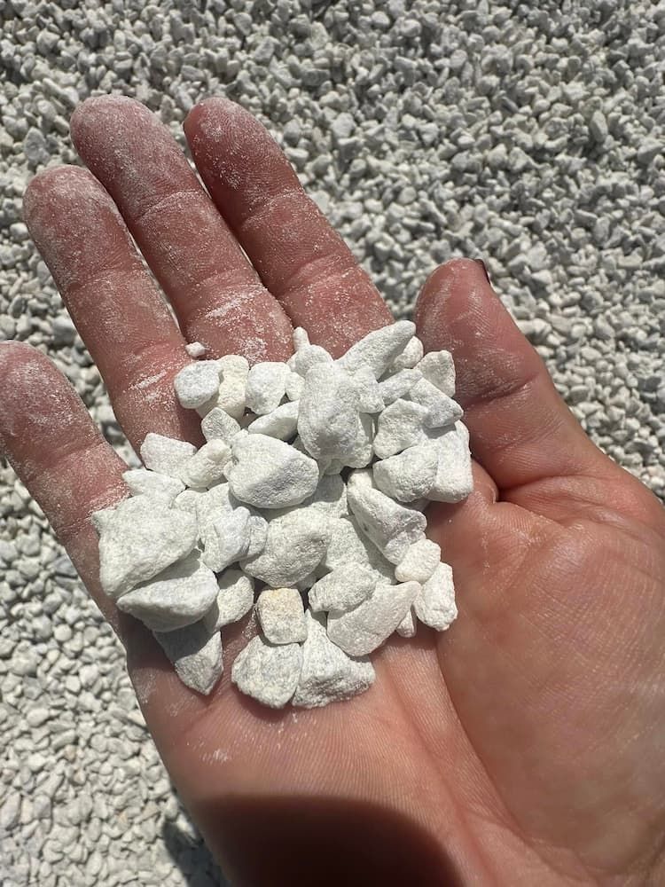 A Person Is Holding A Pile Of White Gravel In Their Hand — Burnetts On Barney in Shoalhaven Heads, NSW