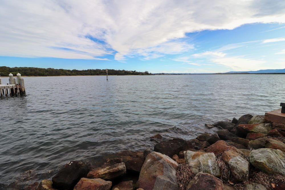 A Large Body Of Water With Rocks In The Foreground And A Dock — Burnetts On Barney in Shoalhaven Heads, NSW