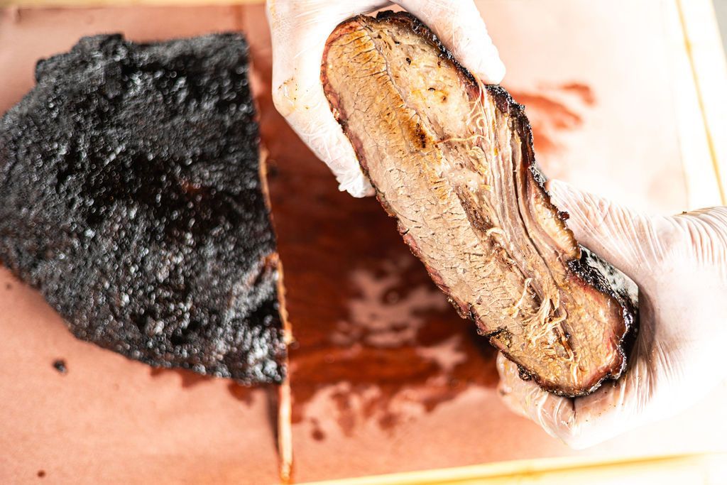 Two split food slices, one burnt black and one browned, on a plate with sauce