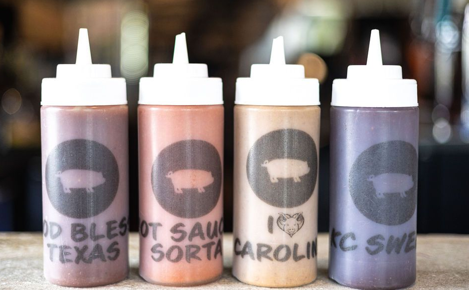 Four squeeze bottles with black labels and white caps, lined up on a table.