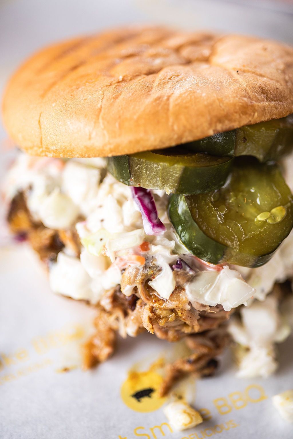 Pulled pork sandwich with pickles and creamy slaw on a plate