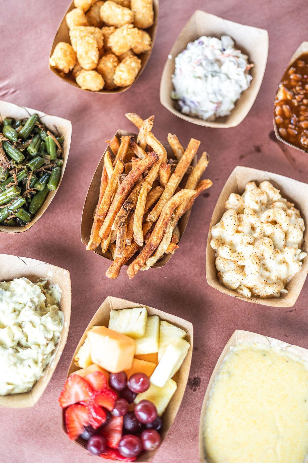Assorted appetizers and desserts in small bowls on a pink tablecloth