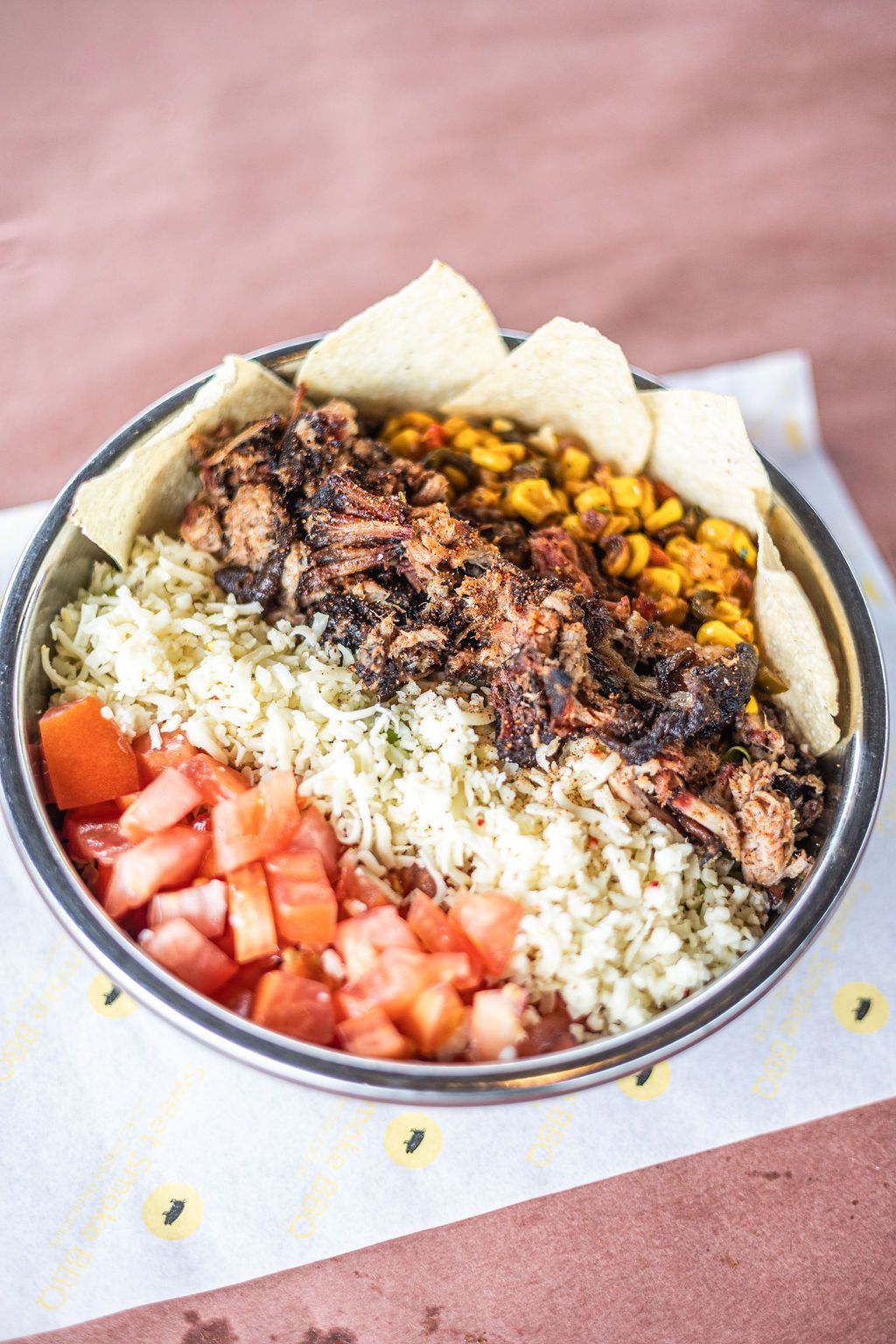 Mediterranean rice bowl with tomatoes, chickpeas, roasted vegetables, meat, and pita chips