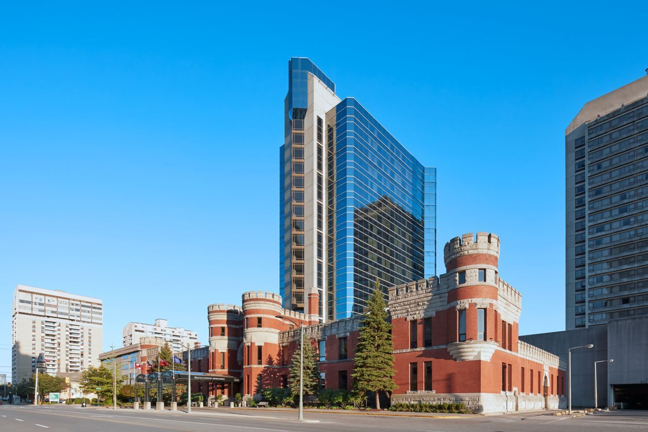 A modern glass skyscraper with a brick castle facade on a clear, sunny day.