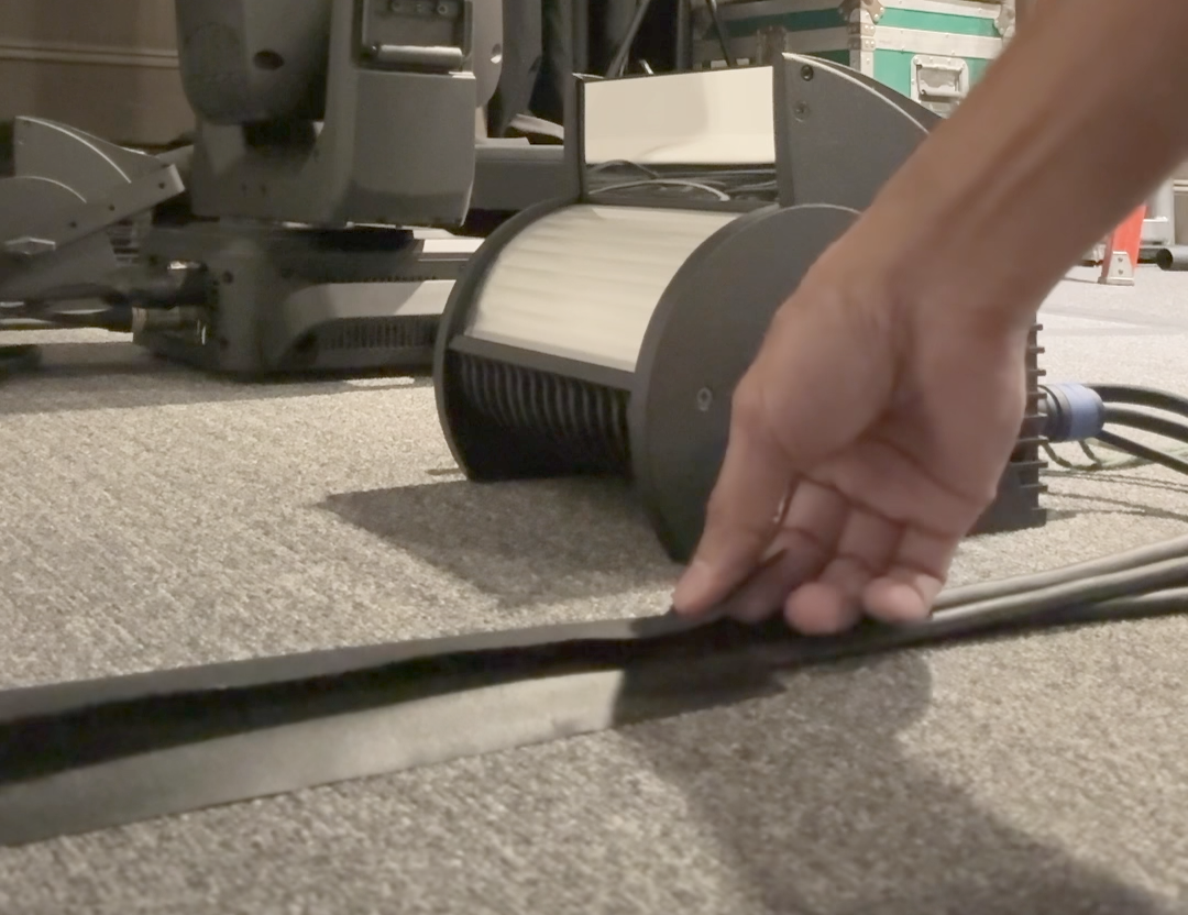 Taping down cables on a carpet to organize the work area with Gaff tapes from Horizon Solutions.