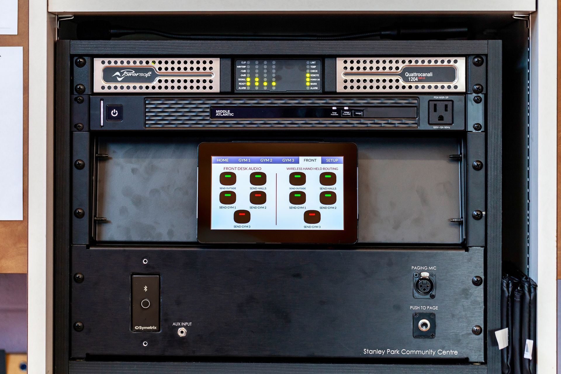 Black rack of audio equipment with a touchscreen control panel.