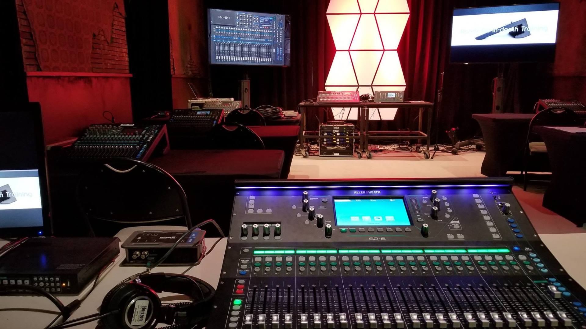 Sound mixing console setup in a dim room with monitors and other equipment.