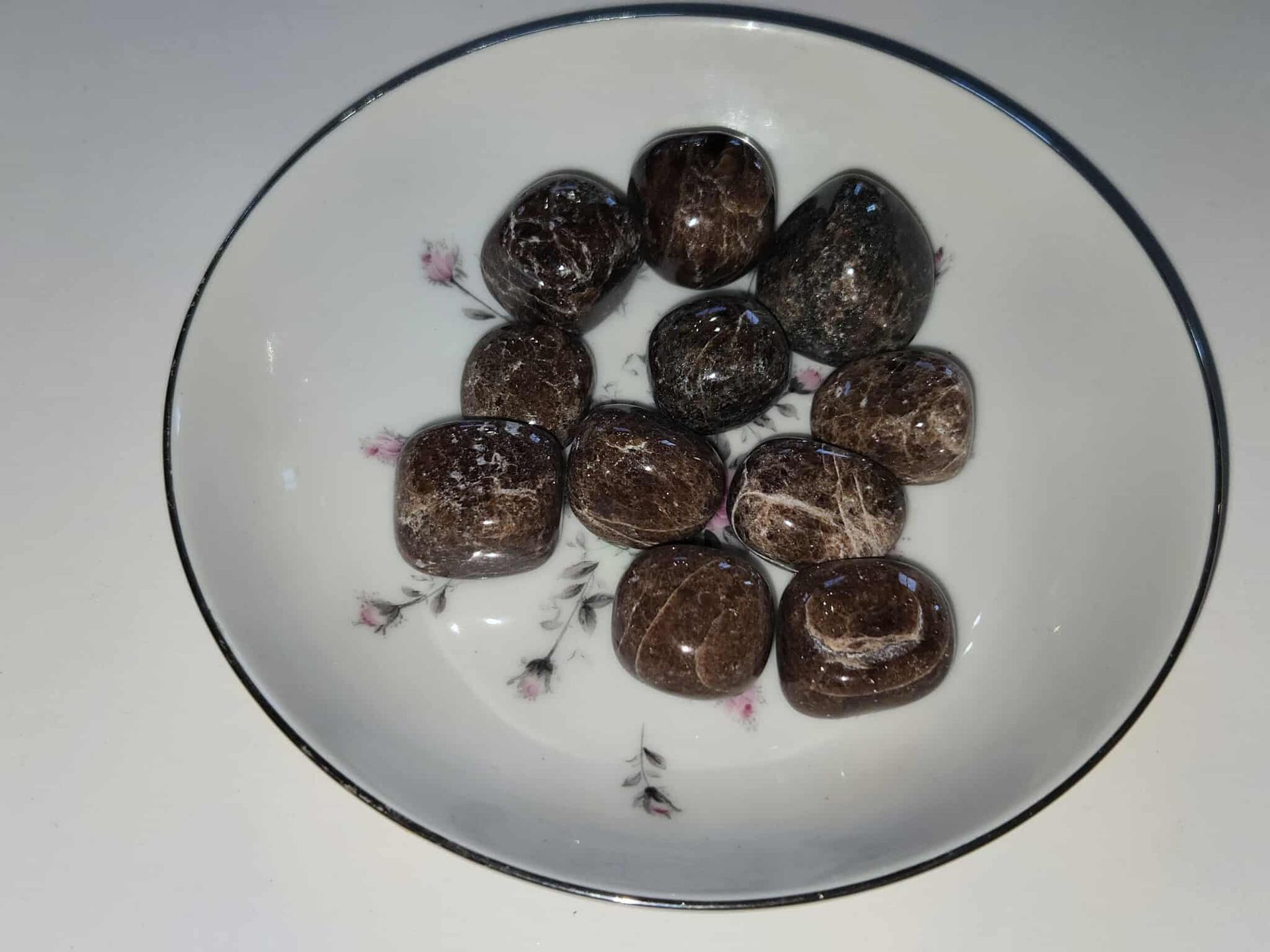 Brown, polished stones in a white floral-decorated bowl.