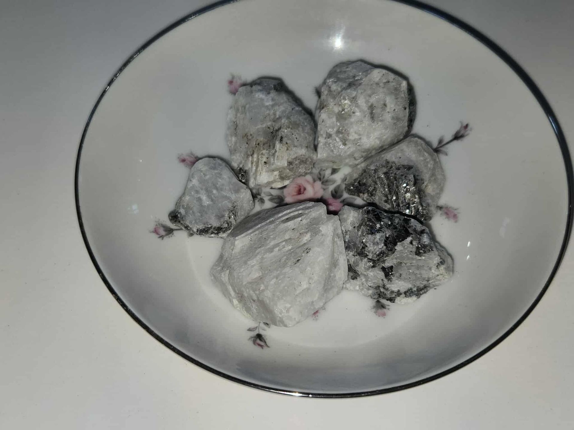 Chunks of a gray, crystalline substance in a floral-decorated white bowl.