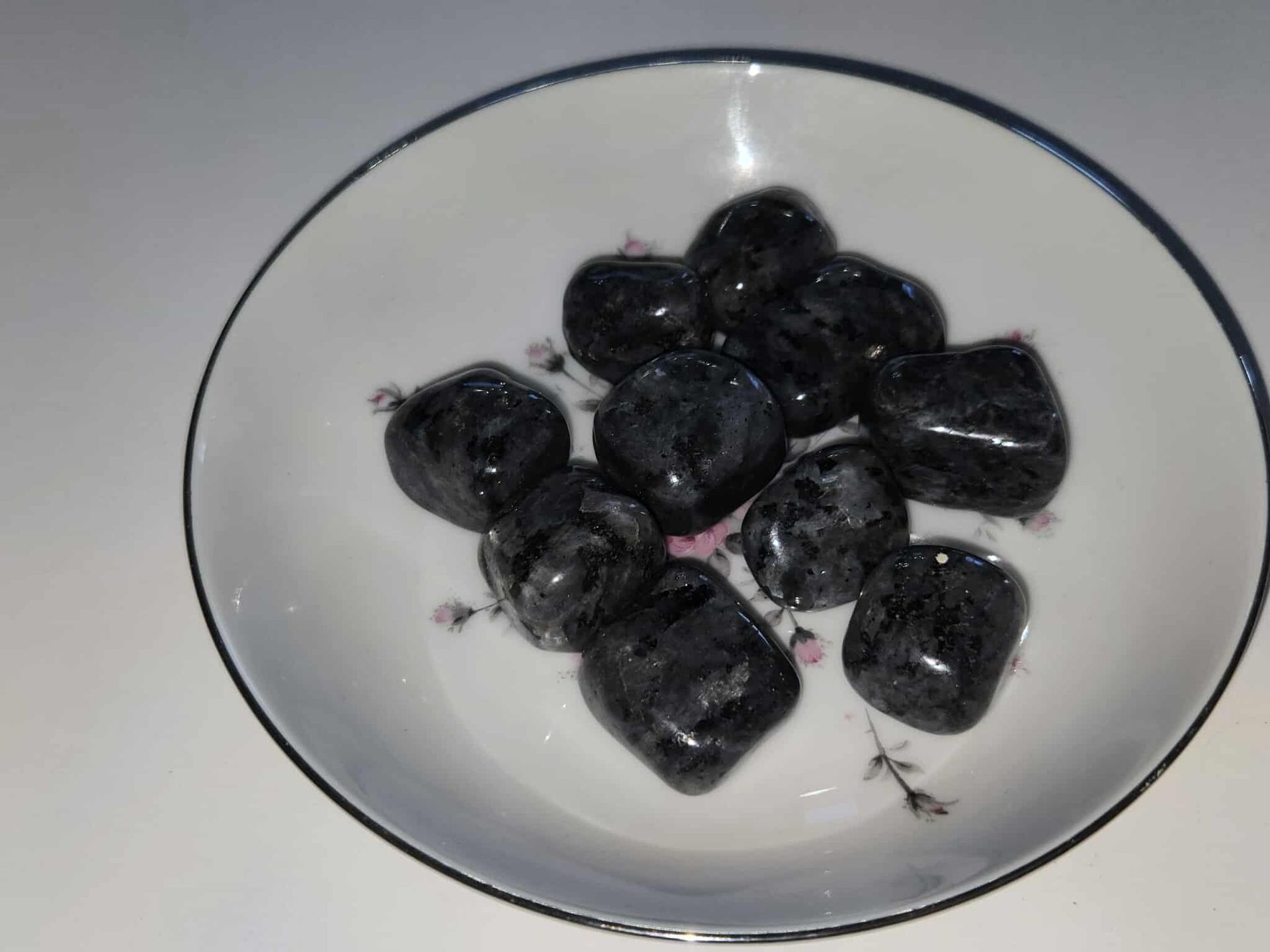 Dark, polished stones in a white bowl with a blue rim and floral design.