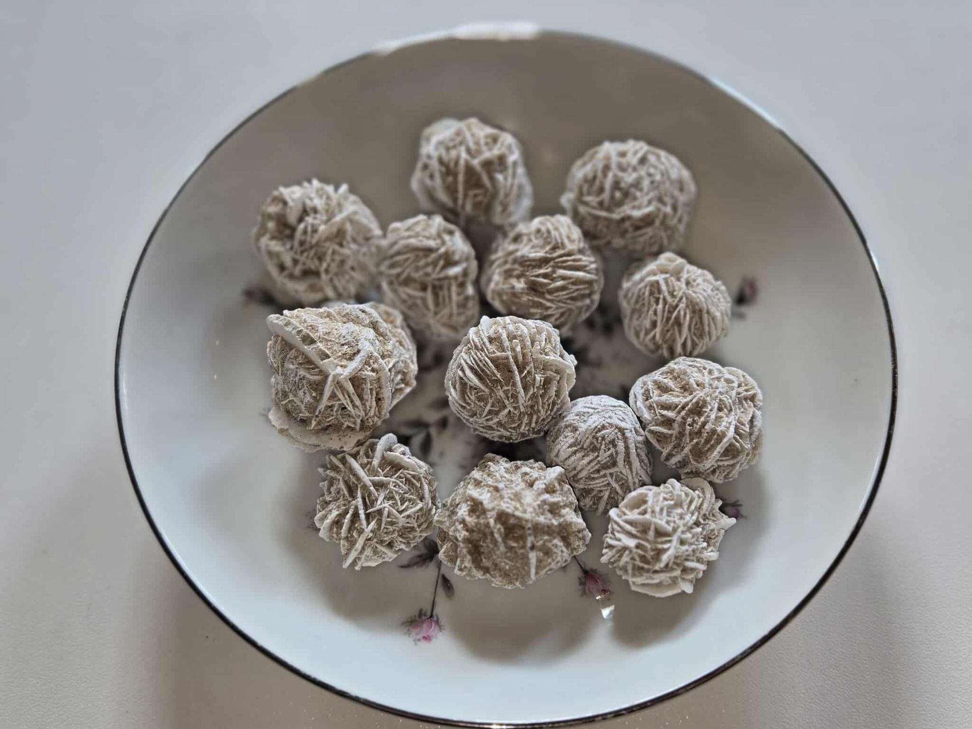 Desert rose crystals in a decorative bowl on a white surface.