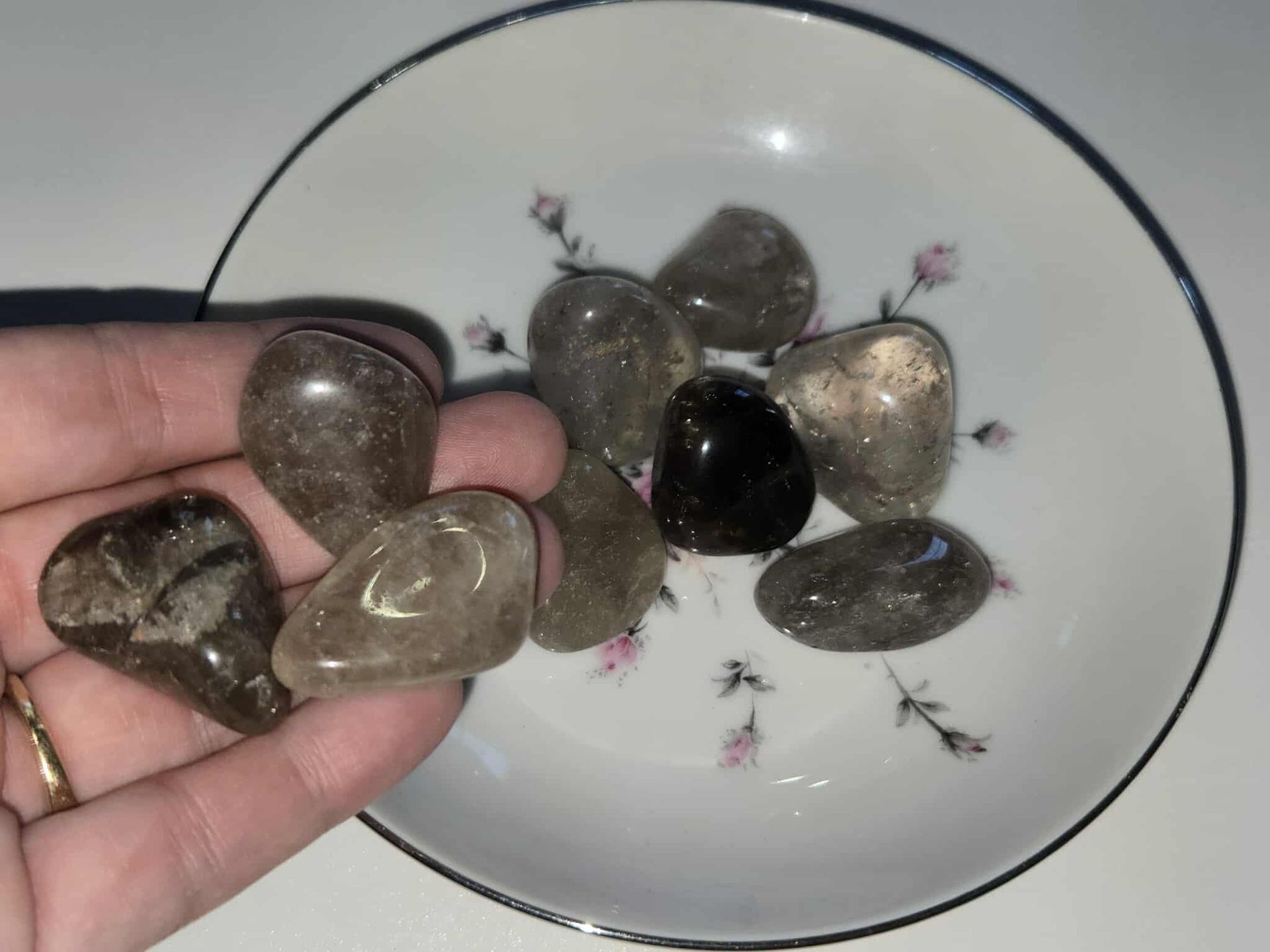 Small white bowl with floral design, holding several gray and black polished stones.