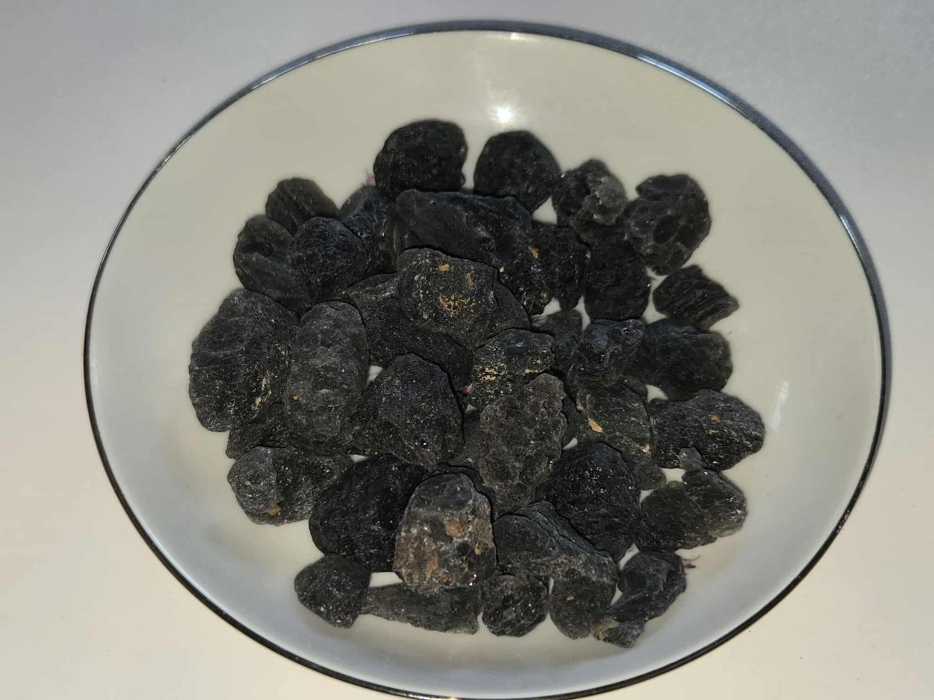 Dried black fruit in a white bowl.