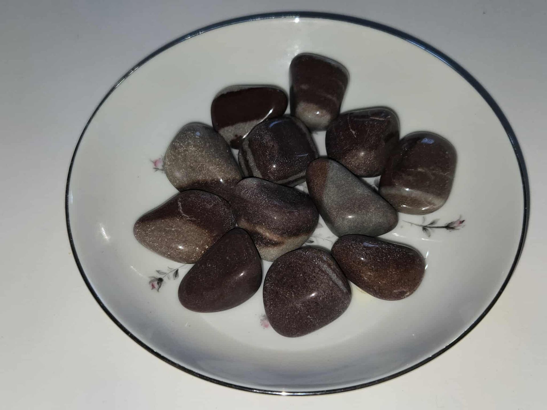 Brown and gray polished stones in a white, decorative dish.