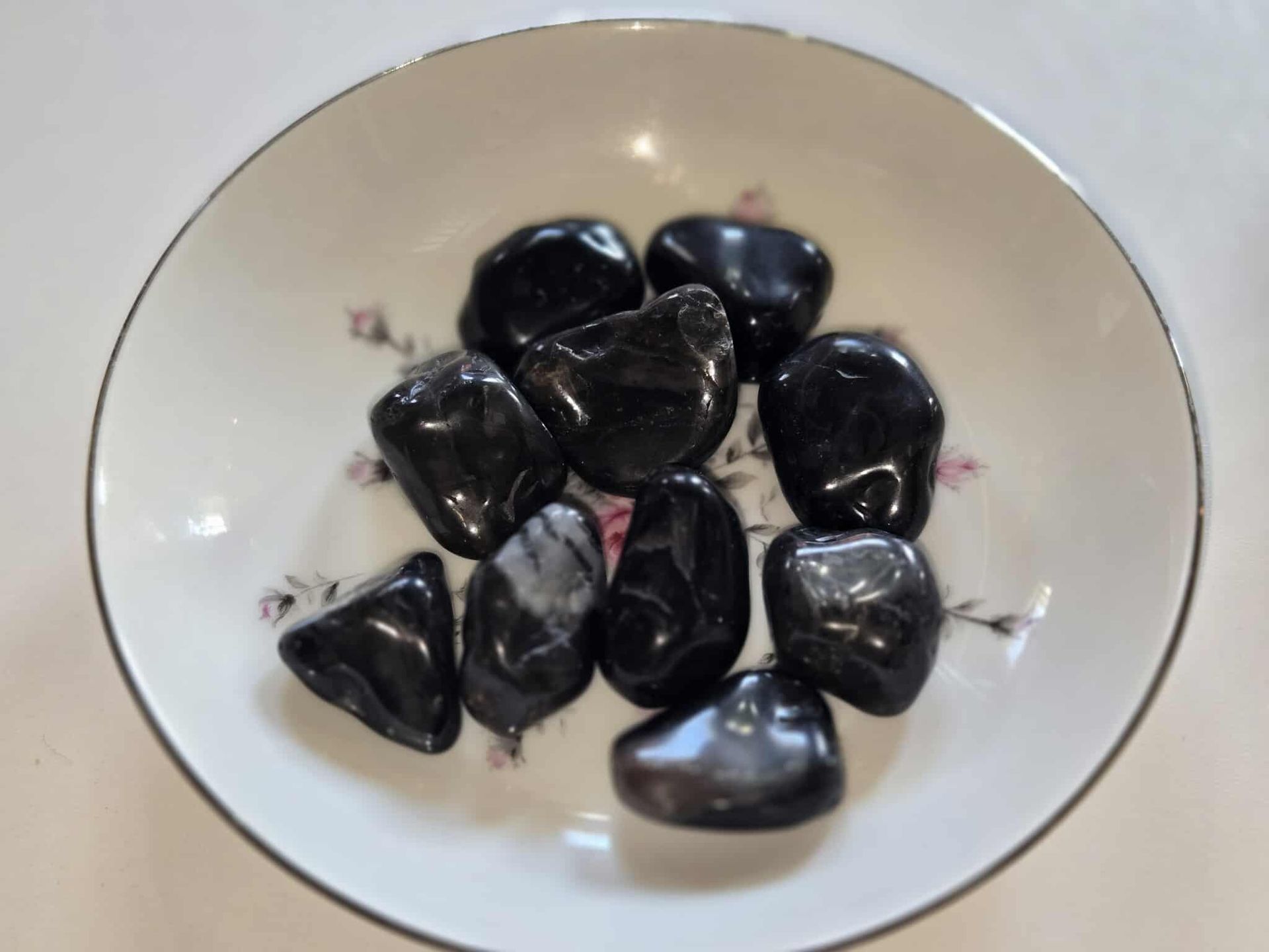 Black, polished stones in a floral patterned, white teacup.