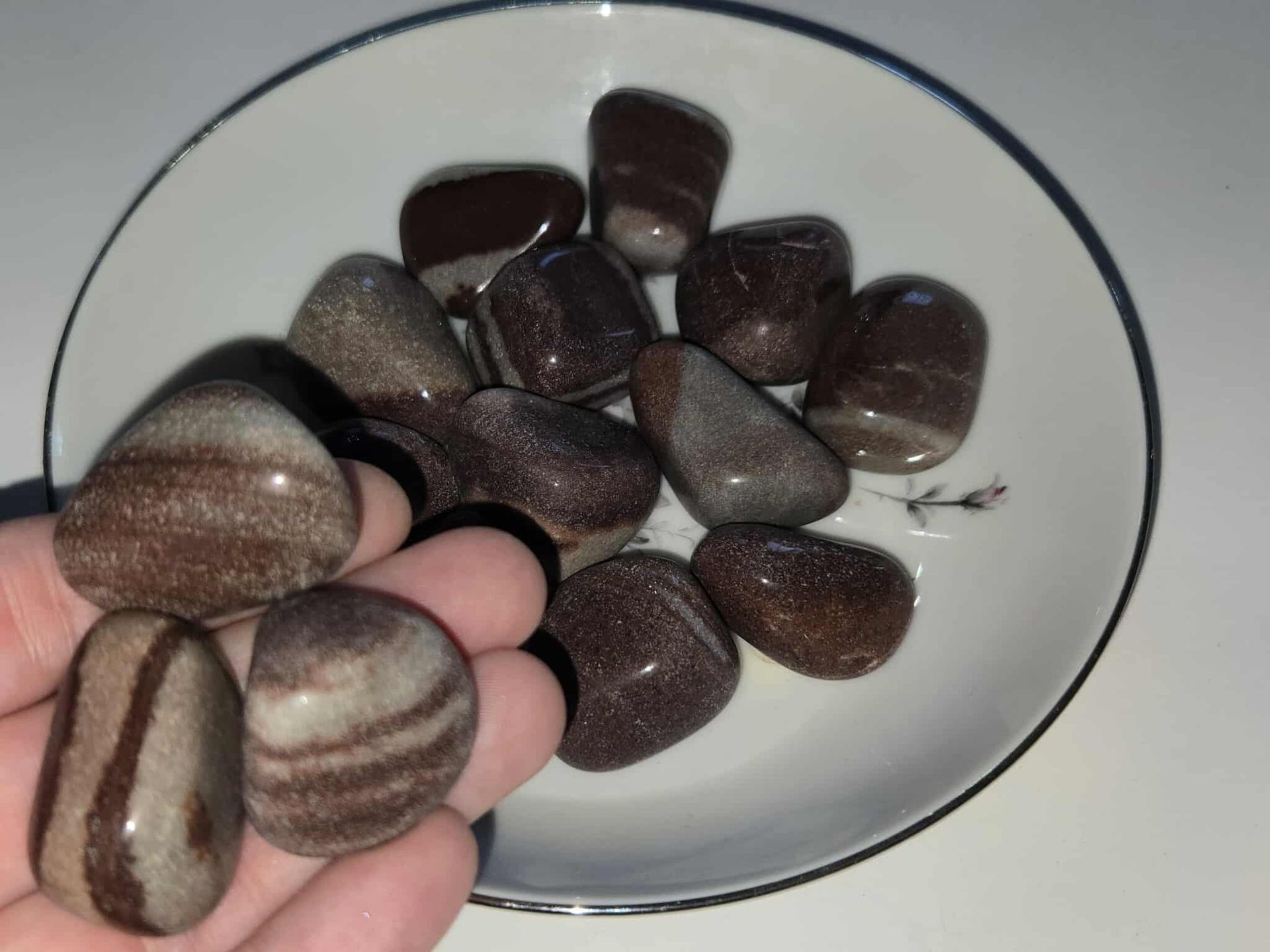 Brown and gray polished stones in a white, decorative dish.