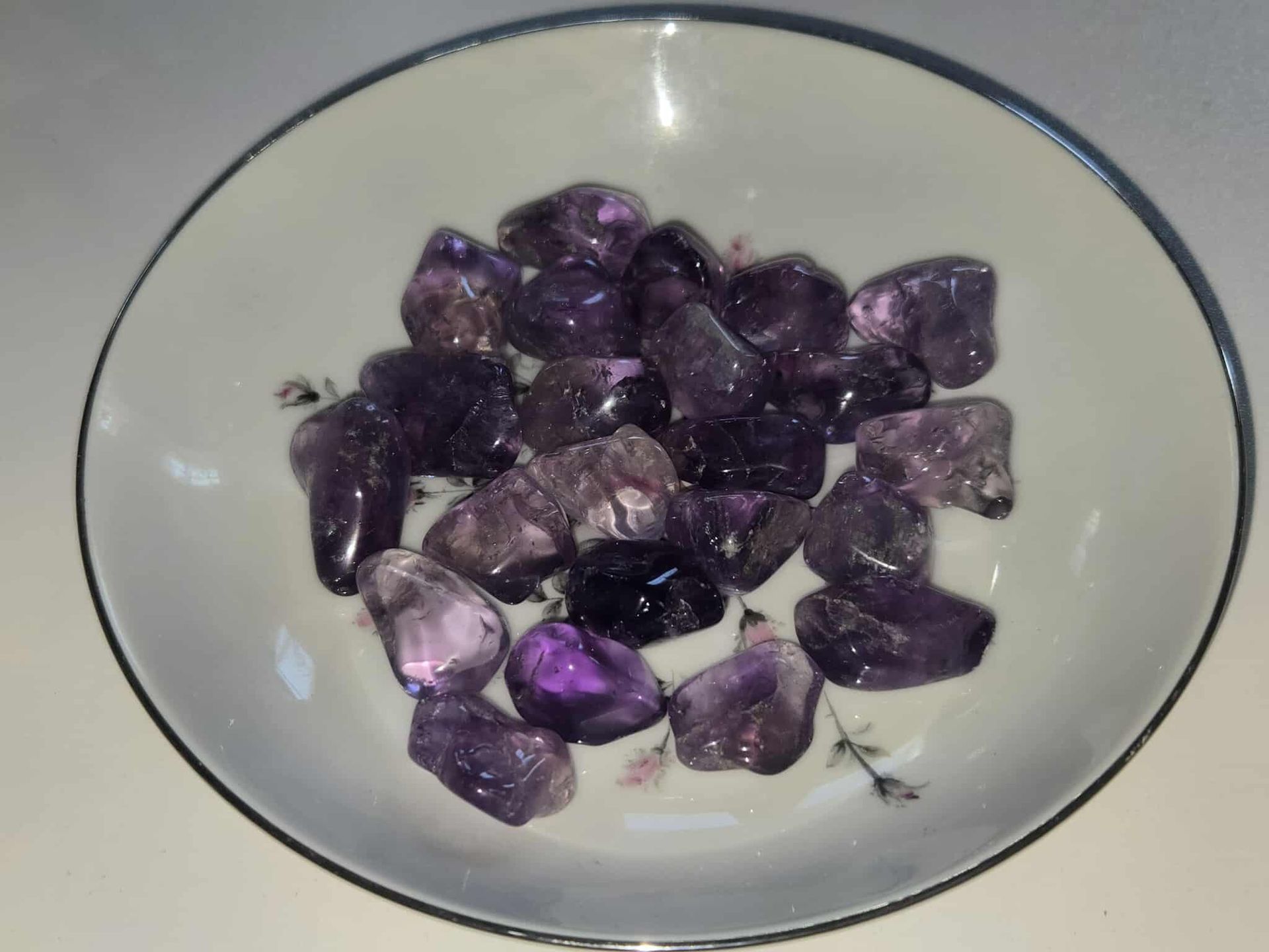 Amethyst crystals in a white bowl with floral design.