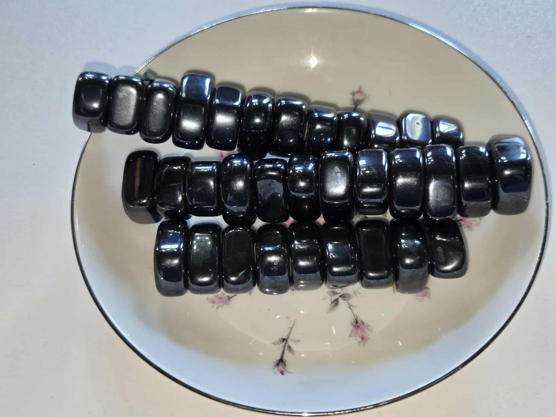Black magnetic beads on a white plate with a floral design.