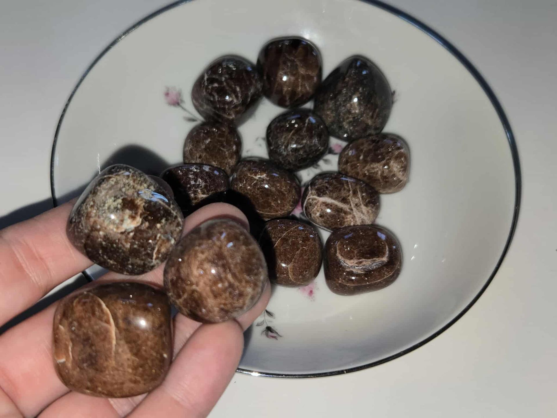Brown, polished stones in a white floral-decorated bowl.