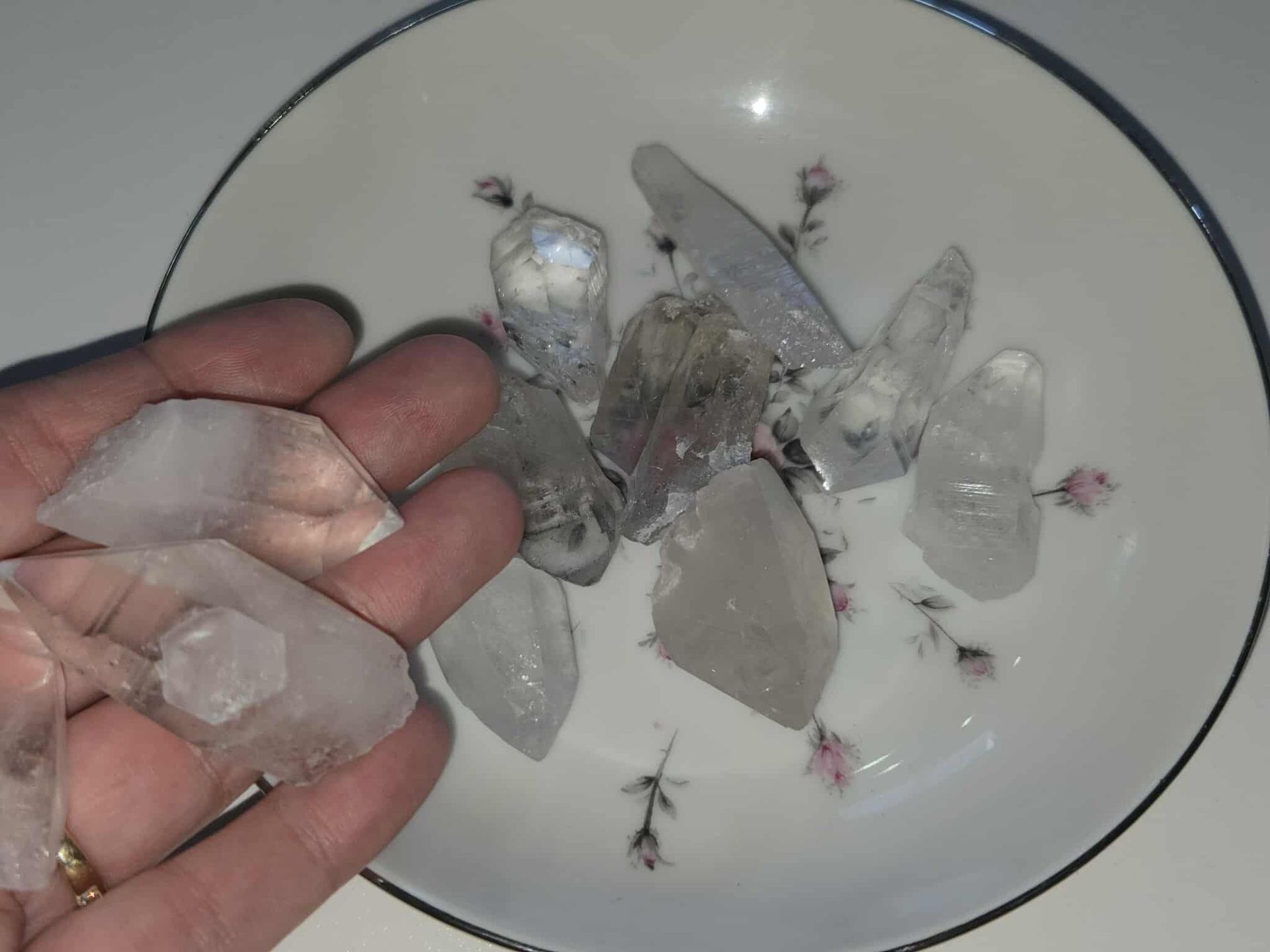Clear quartz crystals arranged in a decorative white bowl with floral patterns.