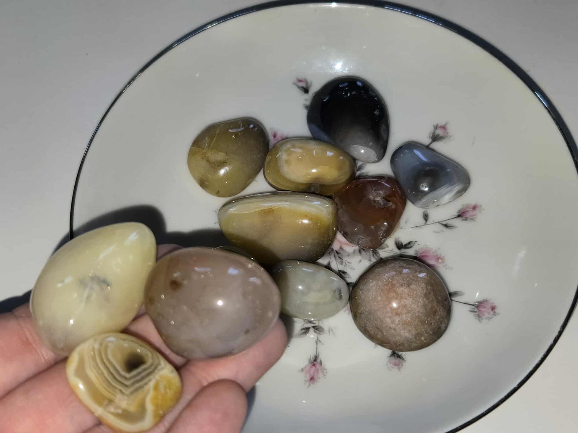Smooth, colorful stones in a decorative floral bowl on a white surface.