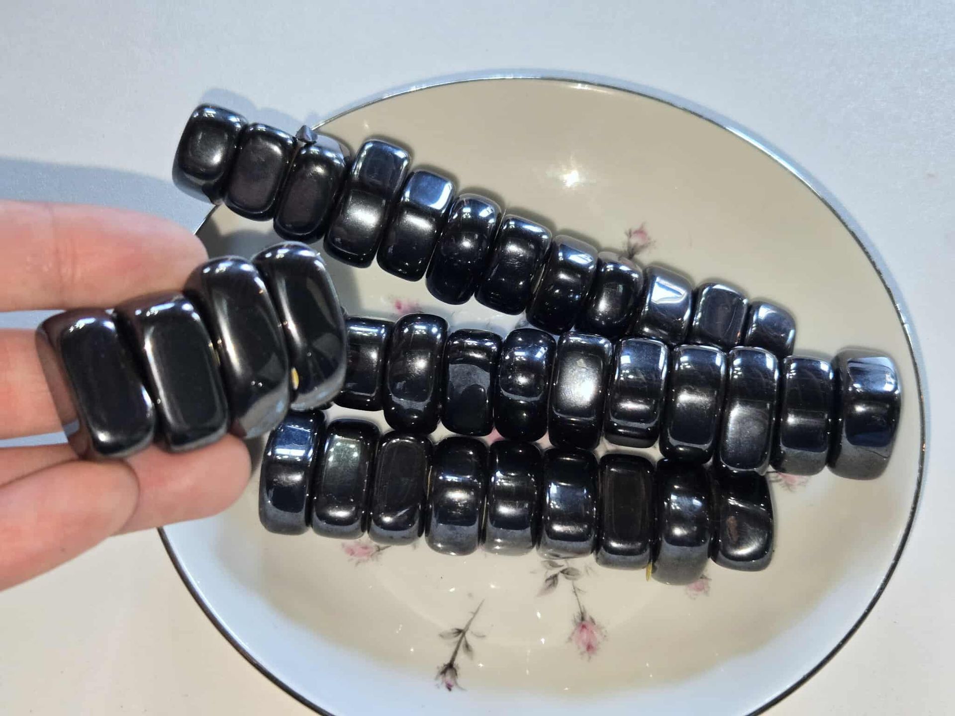 Black magnetic beads on a white plate with a floral design.