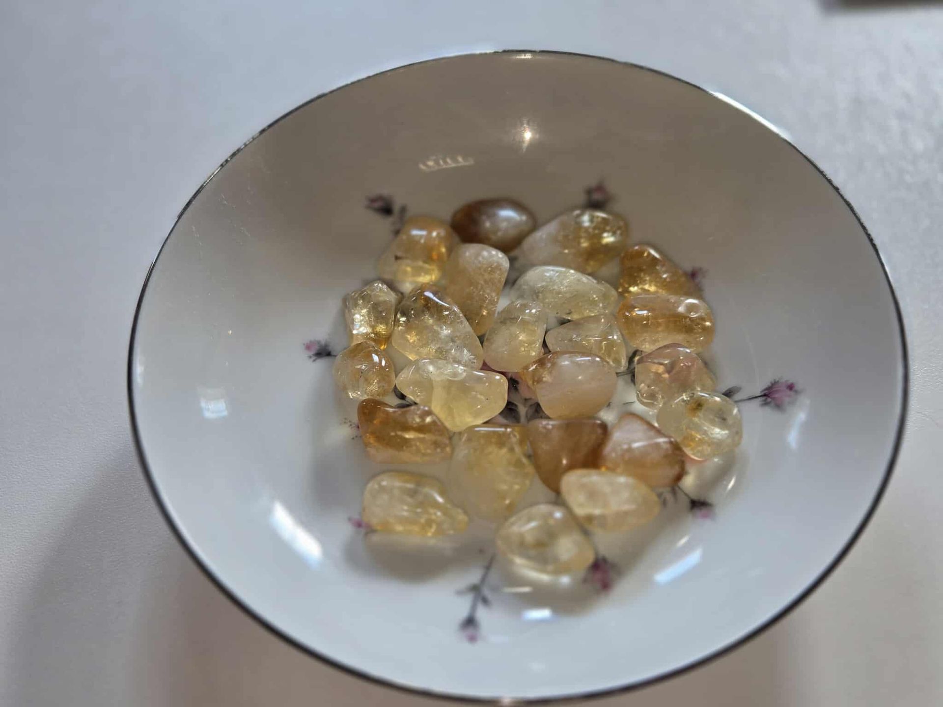 Bowl of yellow-orange citrine crystals on a white plate with a floral design.