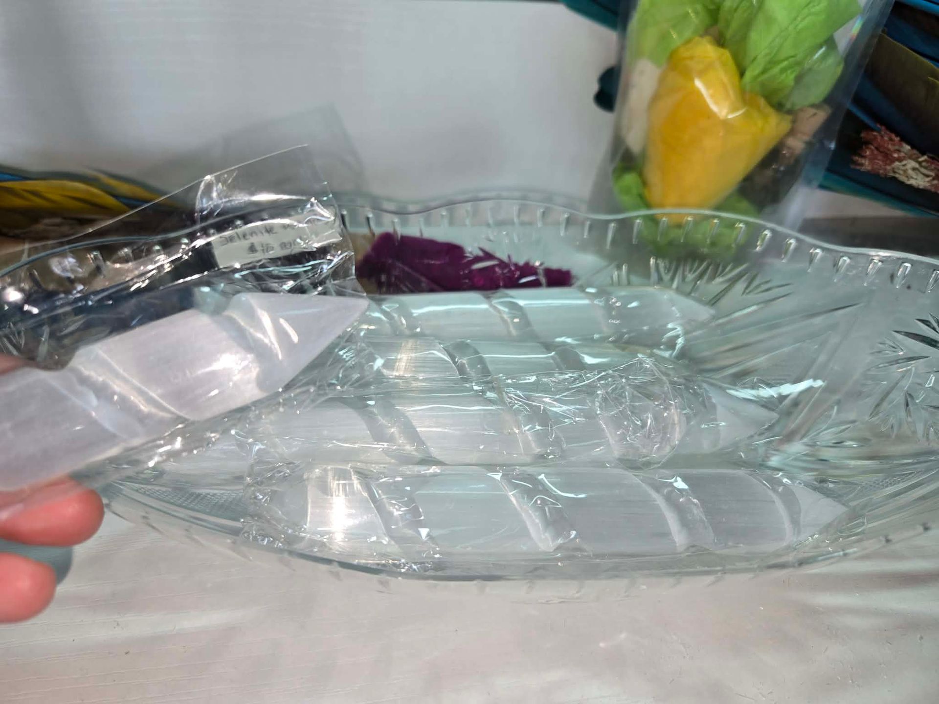 Clear glass serving dish with wrapped white crystals inside. A hand holds the dish.