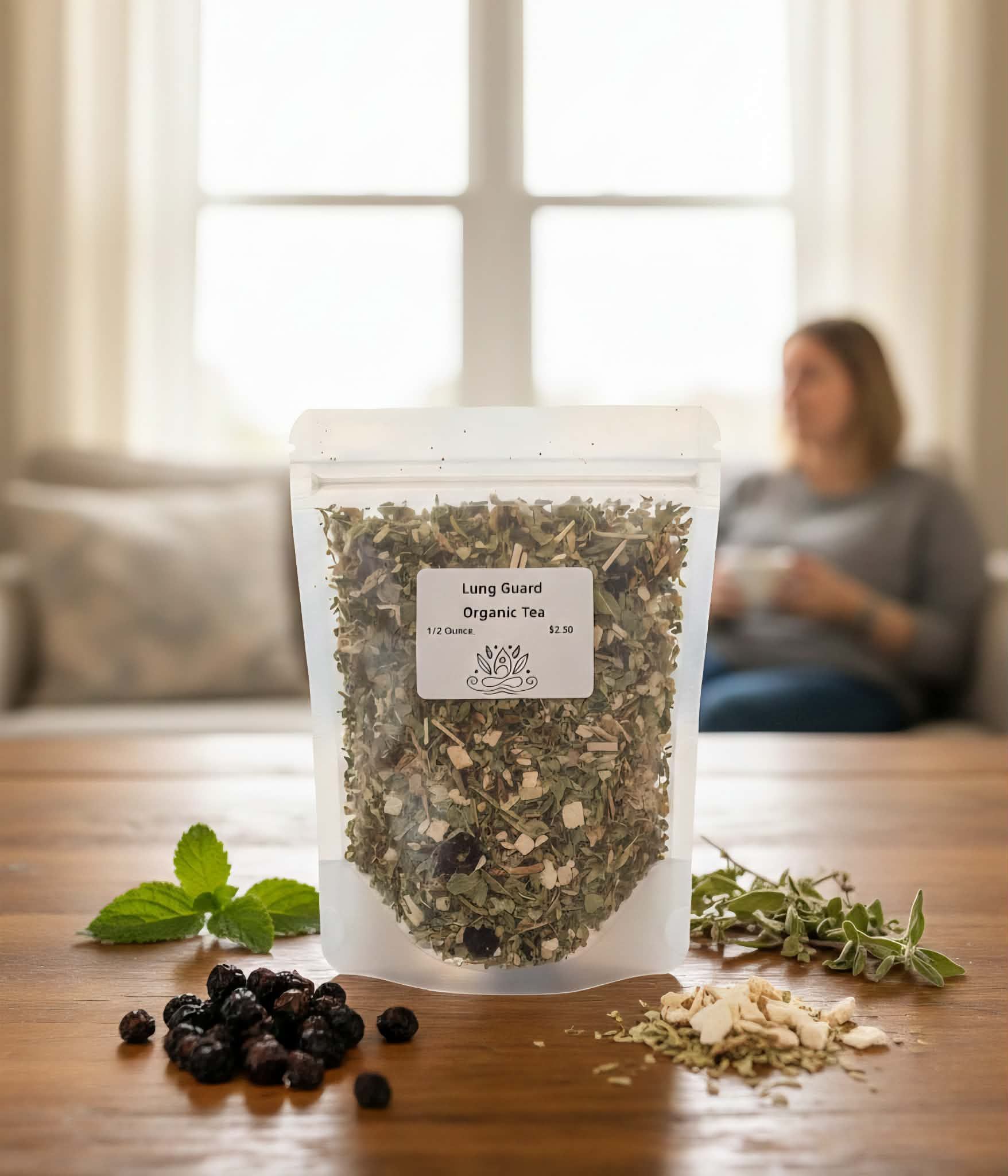 Bag of herbal tea on a wooden table with fresh herbs and berries. A person sits in the background near a window.