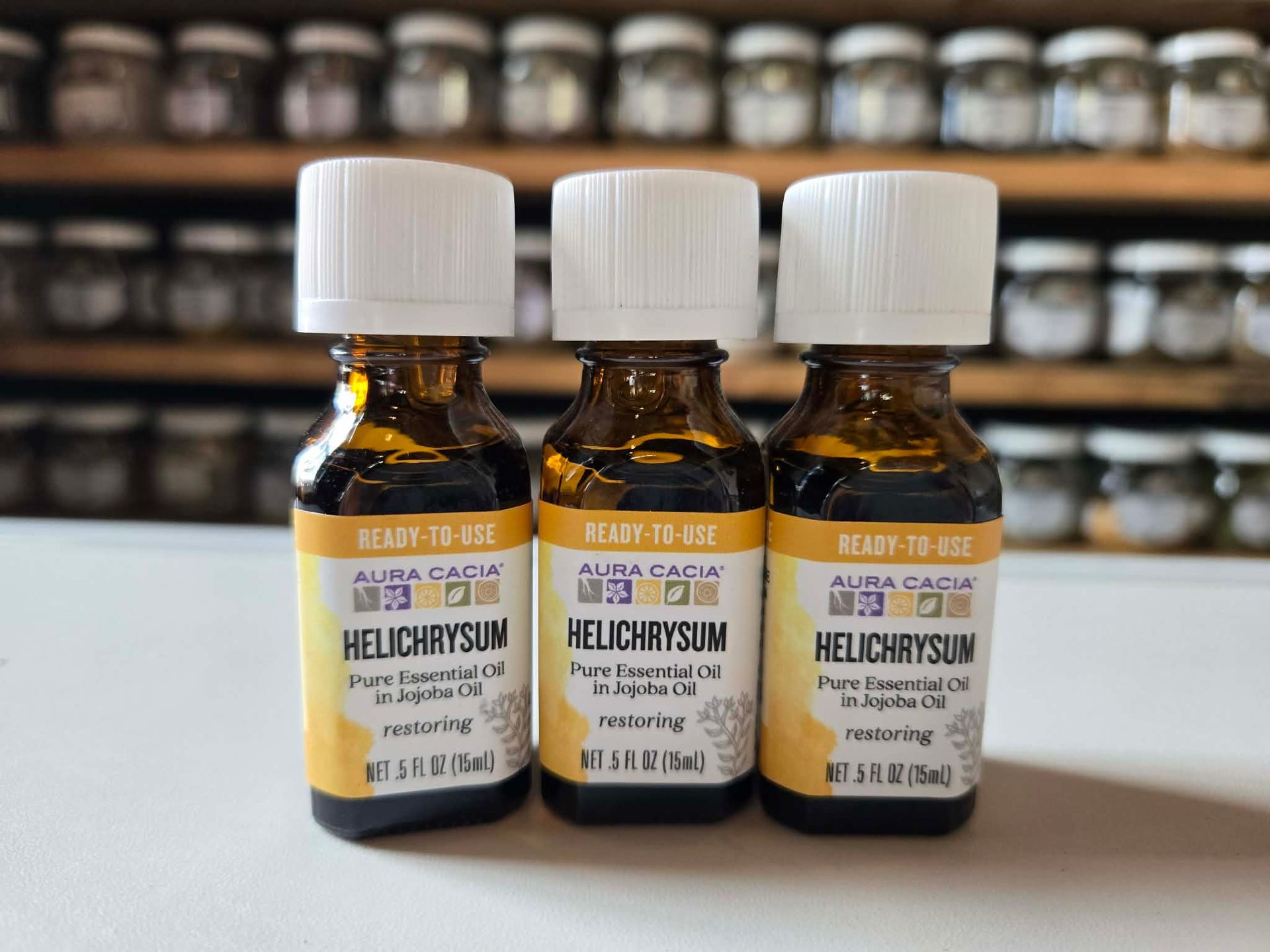 Three amber prescription bottles on a shelf, with white caps and blurred jars in the background.