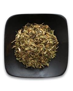A black bowl filled with dried herbs on a white background.