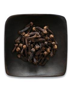 A black bowl filled with cloves on a white background.