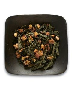 A black square plate topped with green tea leaves and fruit.
