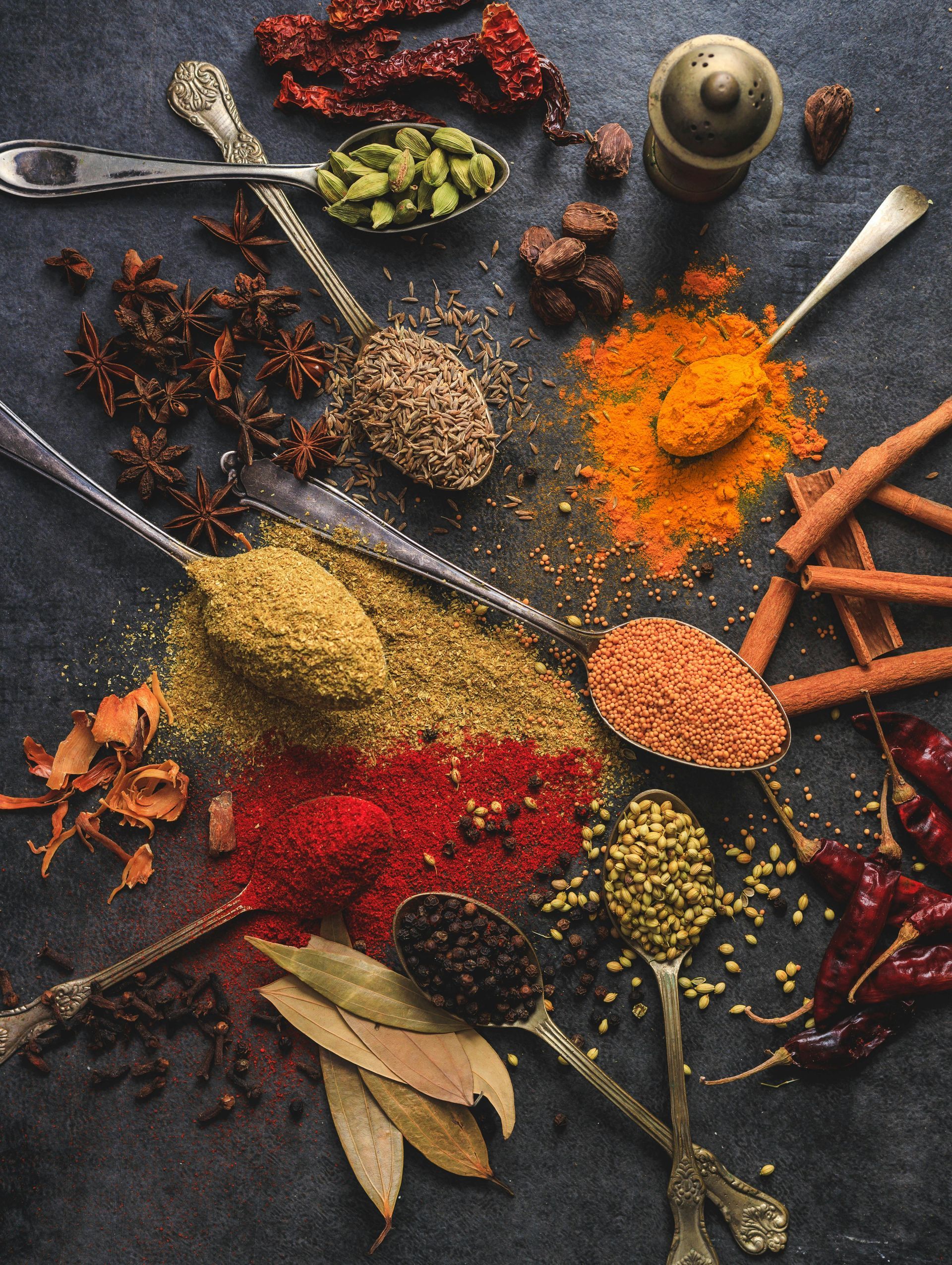 A variety of spices in spoons on a table