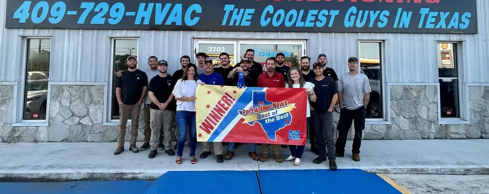 Group posing outside 409-729-HVAC storefront holding a colorful banner, with “The Coolest Guys in Texas” sign above.